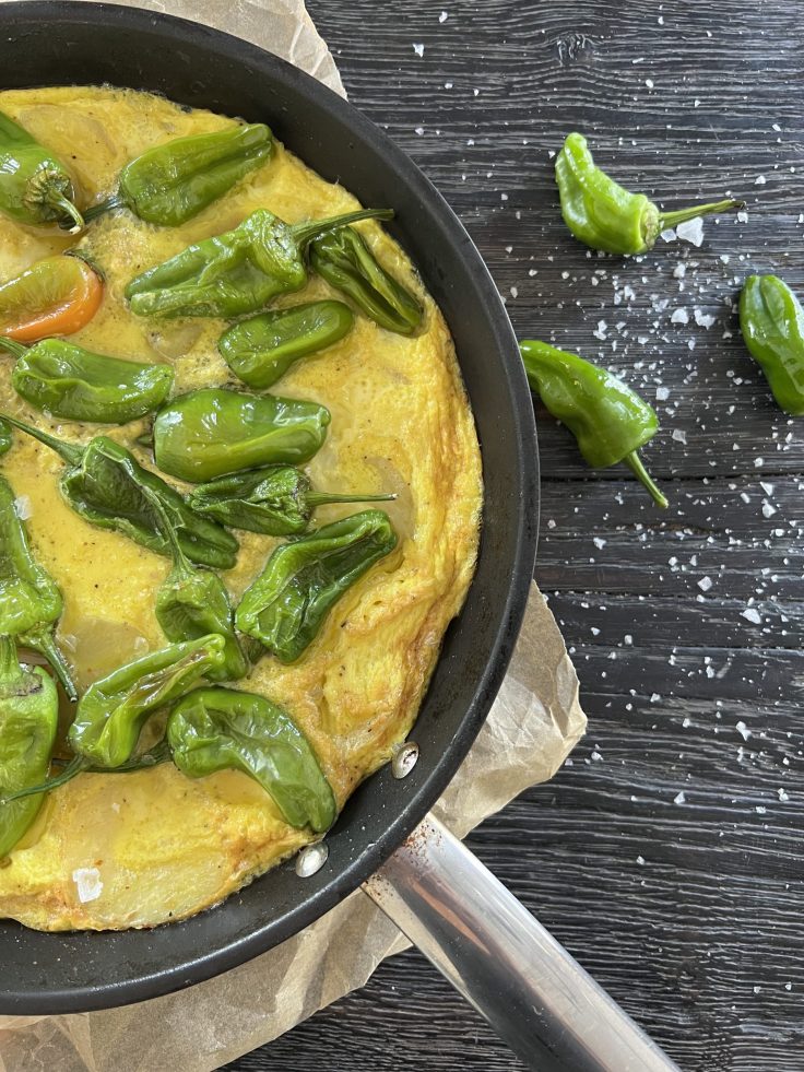Spansk-tortilla-serveret-med-pimientos-del-padron-paa-toppen