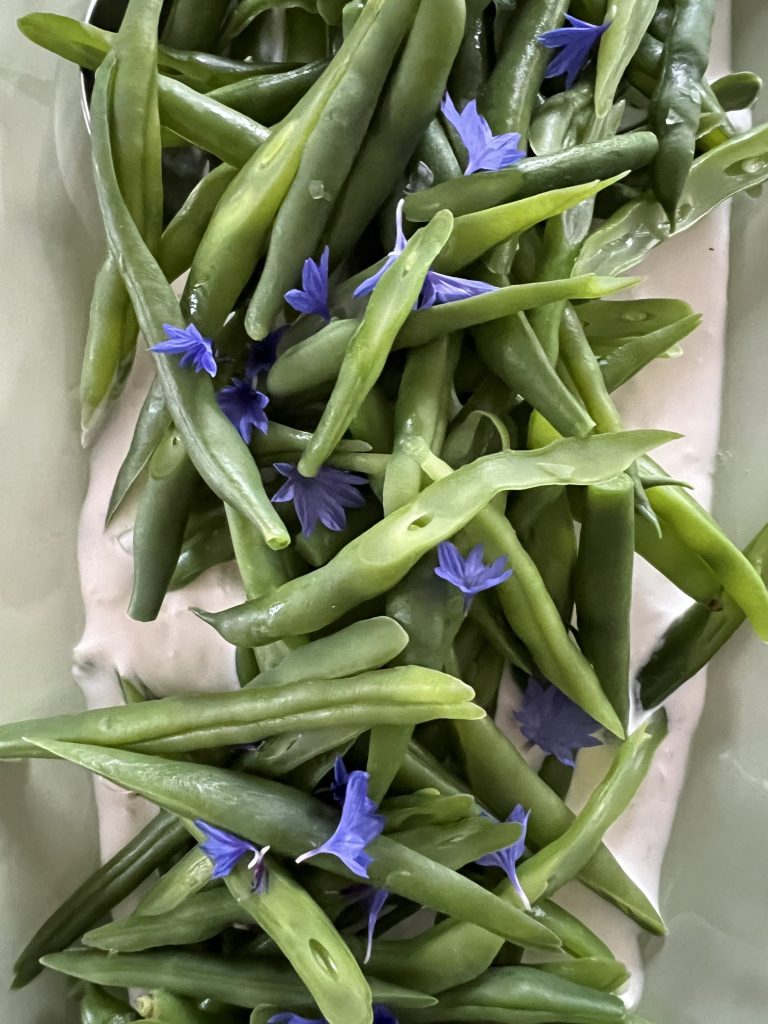 bønner lagt på bund af hvid dressing og pyntet med blå blomster